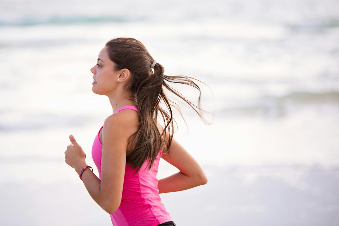 Young woman in pink athletic wear running outdoors, symbolizing natural energy, endurance, and healthy lifestyle support