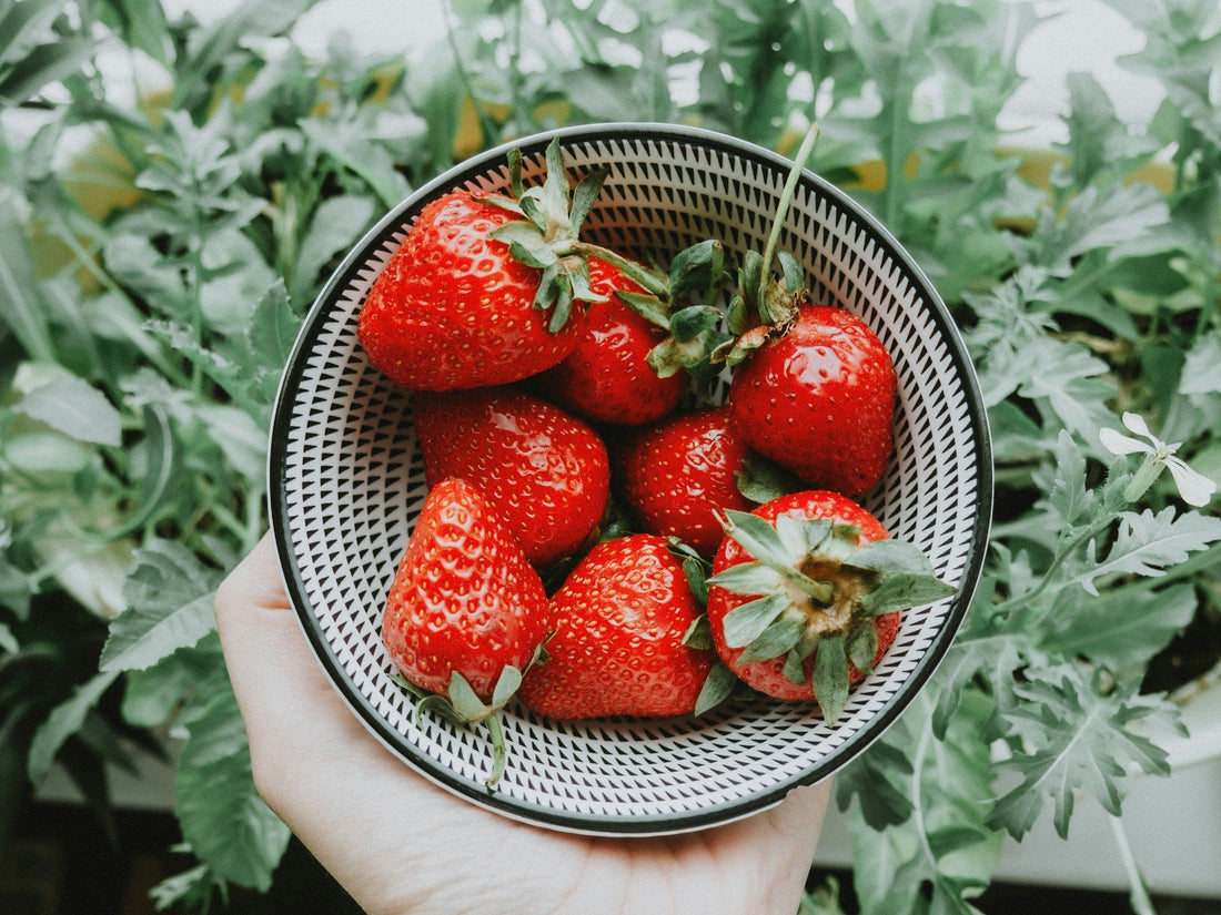 Fresh strawberries in a wooden bowl with greens, highlighting their natural health benefits including antioxidants, heart support, and anti-inflammatory properties.