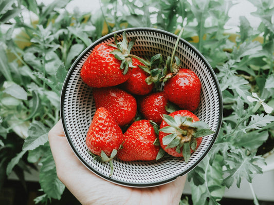 Fresh strawberries in a wooden bowl with greens, highlighting their natural health benefits including antioxidants, heart support, and anti-inflammatory properties.