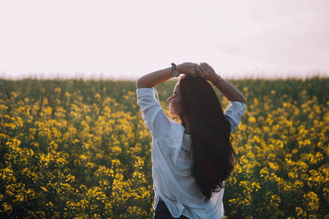 Woman enjoying a peaceful moment in a field of flowers at sunset, reflecting the calming and energizing effects of adaptogens and nootropics