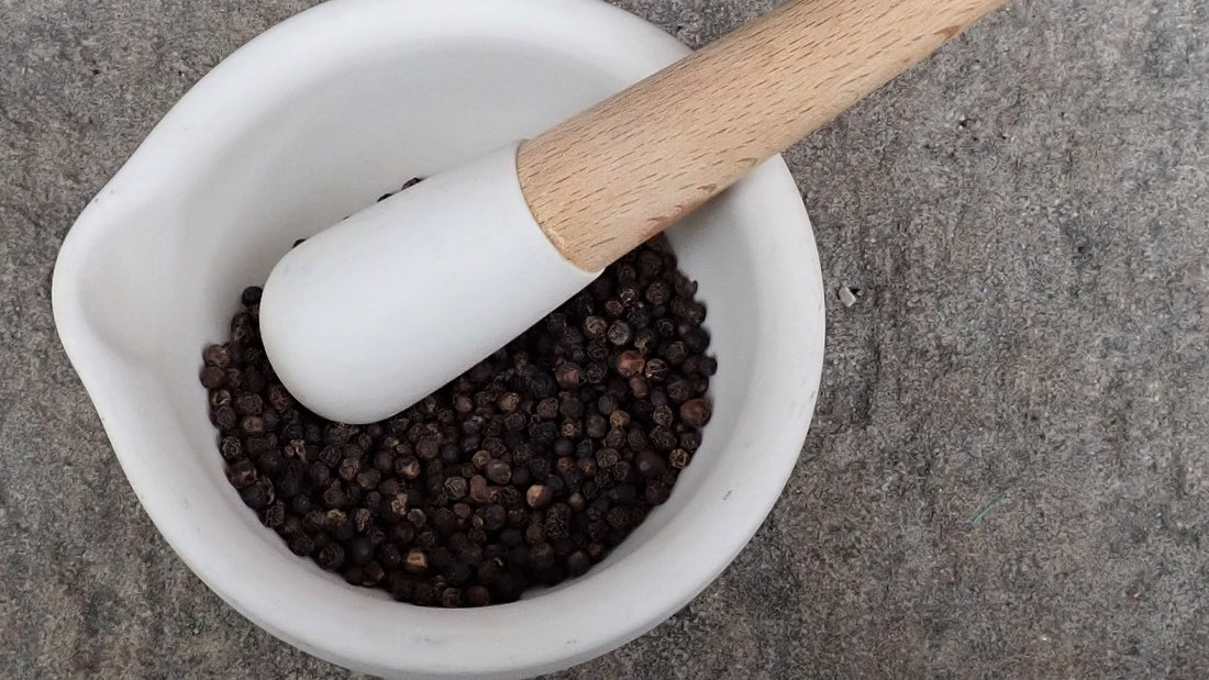 white mortar and pestle with black pepper