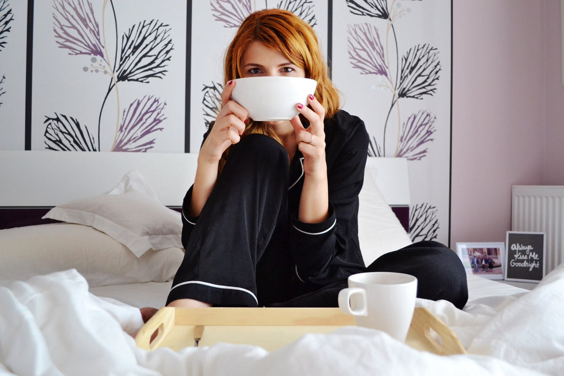 Woman sitting in bed drinking a cup of tea