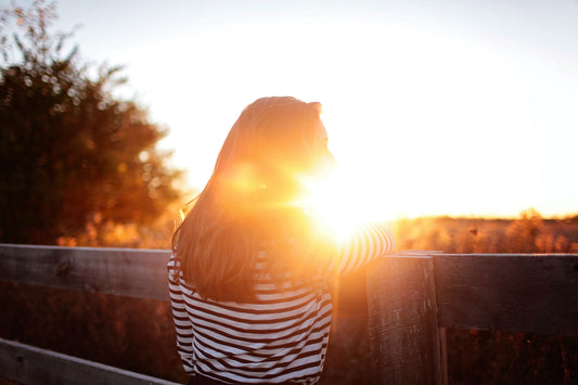 Woman standing with sun shining