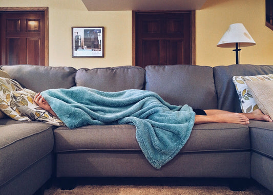 Man laying on the couch with a blanket