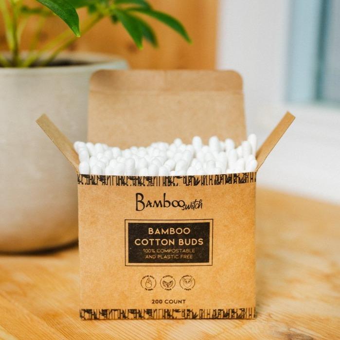 Box of Bamboo Switch bamboo cotton buds on a wooden surface with a plant in the background