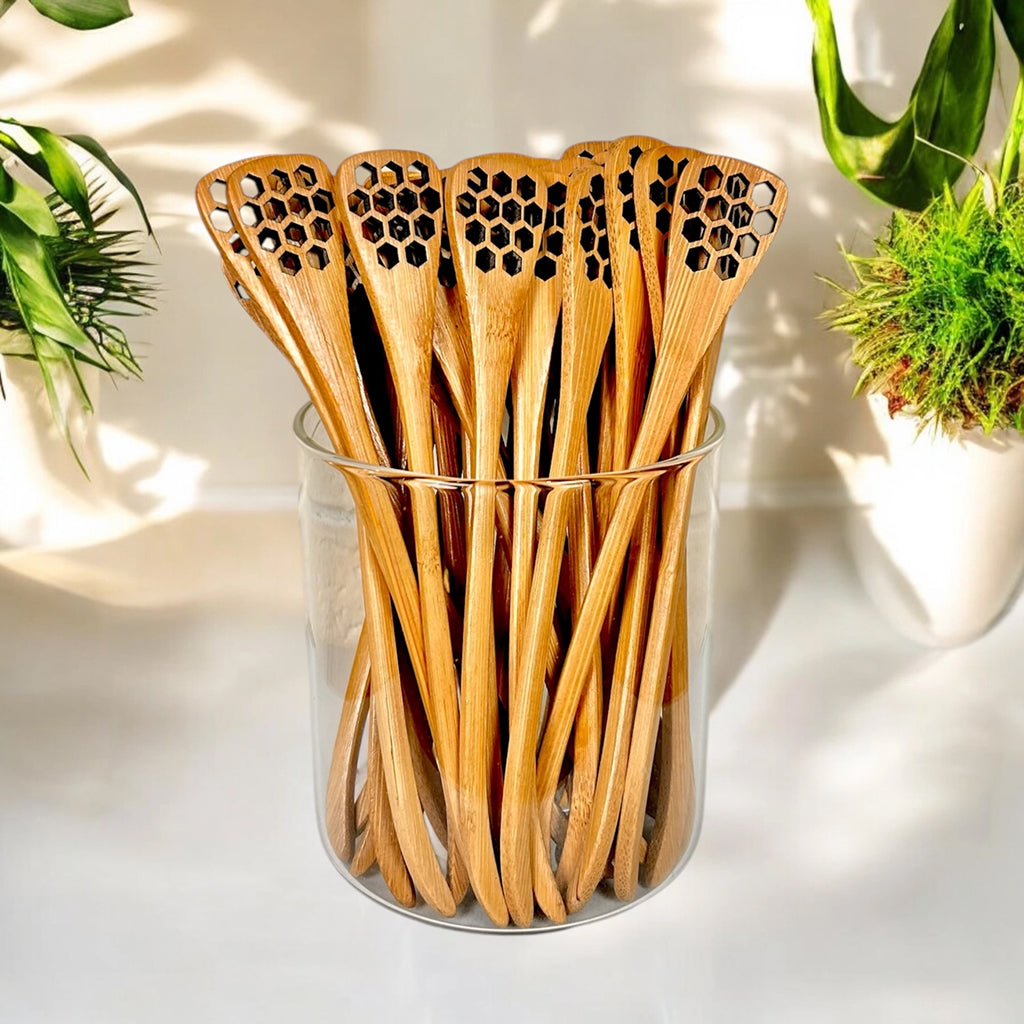 Set of bamboo honey dippers with honeycomb pattern in a glass container on a light background