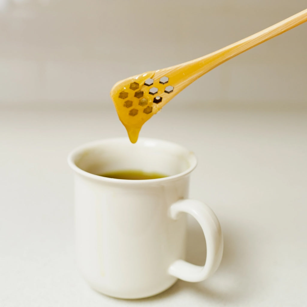White mug with a bamboo honey dipper with honey dripping on a light background