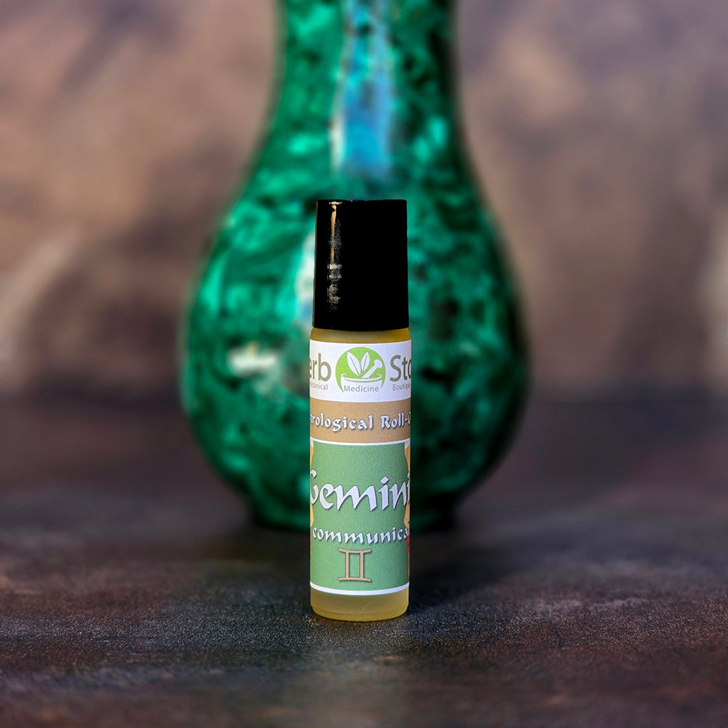 Gemini Aromatherapy Roll-On with a on a dark surface with a blurred malachite decorative vase in the background