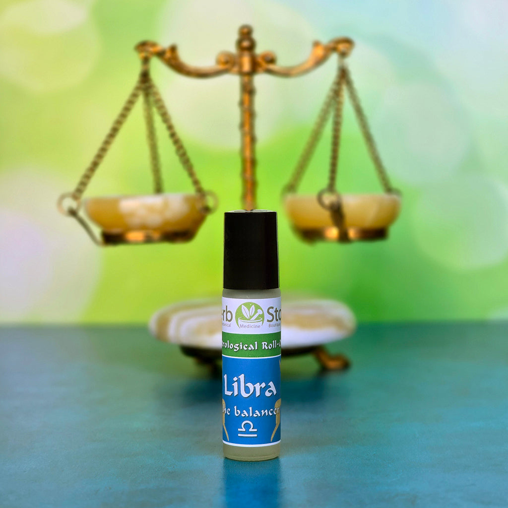 Libra Aromatherapy Roll-on bottle ' with a blurred scale in the background on a blue and green surface.