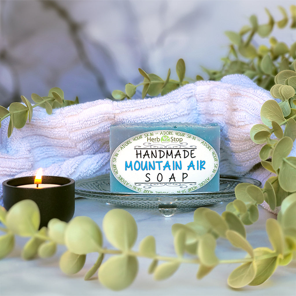 Mountain Air Handmade Soap surrounded by eucalyptus and a lit candle