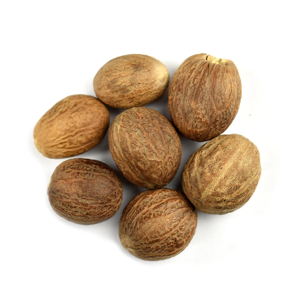 A group of whole organic nutmeg on a white background