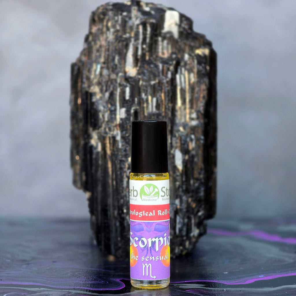 Scorpion Aromatherapy Roll-On bottle in front of a large black tourmaline crystal on a dark surface.