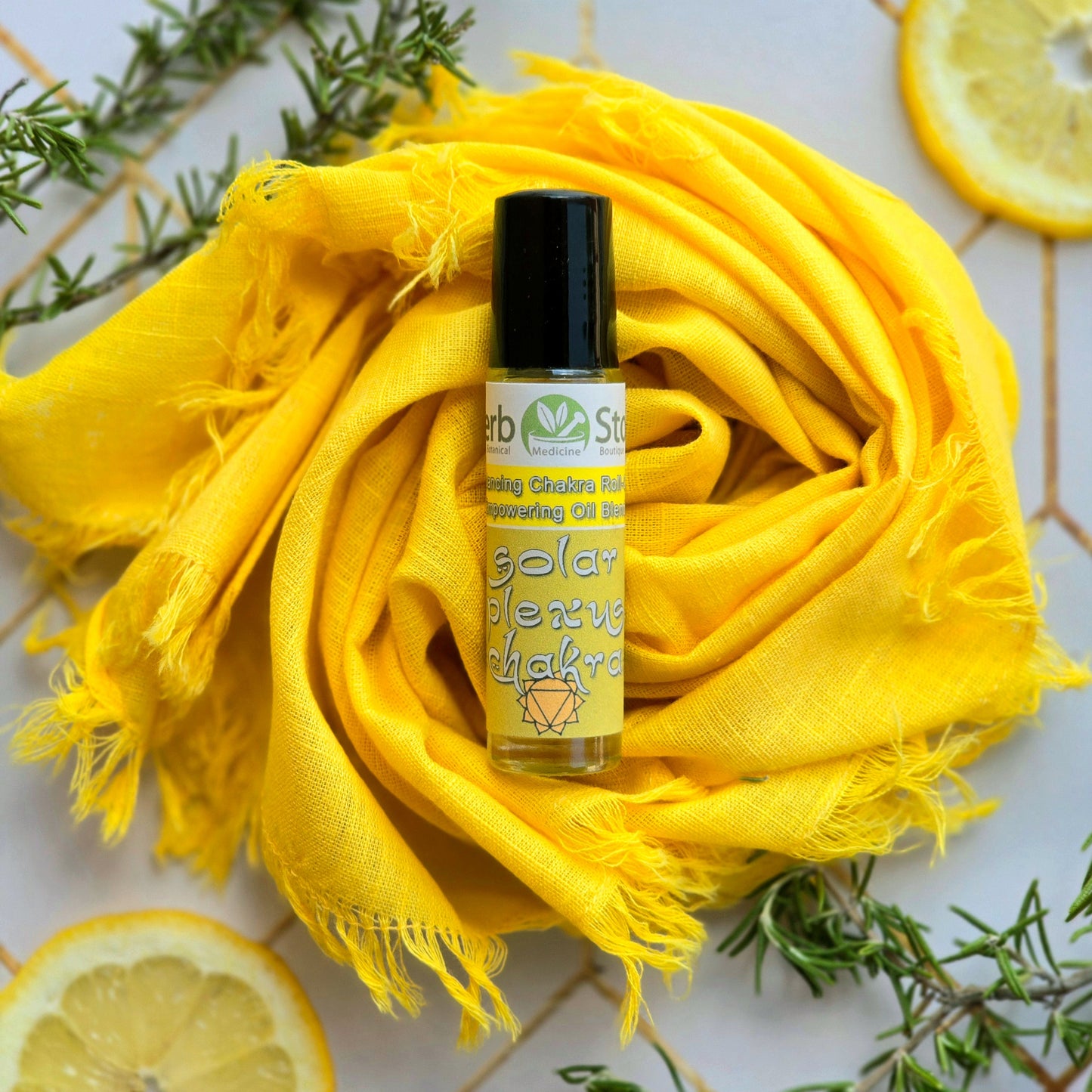 Solar Plexus Chakra Roll-On on a yellow cloth with rosemary and lemon