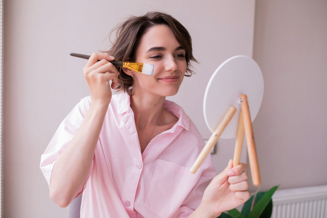 Young woman applying a facial mask as part of a simple preventative skincare routine for healthy, youthful skin.