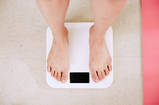 Person standing on a bathroom scale while exploring natural GLP-1 support and healthy weight-loss options