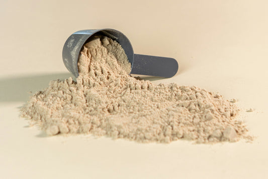 Protein powder spilled from scoop representing protein supplements that may cause bloating