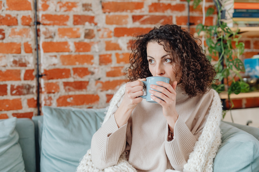 Woman relaxing on couch drinking herbal tea to support perimenopause symptoms naturally