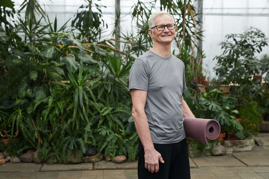 Man standing and holding a yoga mat