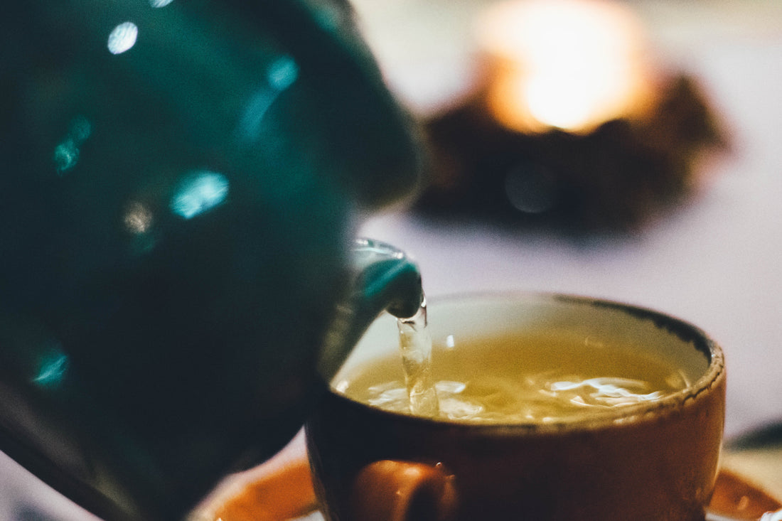 Pouring hot tea from a teapot into a teacup 