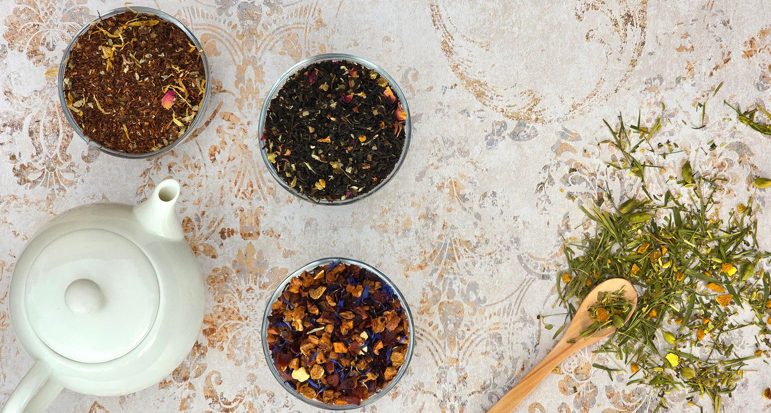 Loose leaf tea in bowls with a teapot and wooden spoon