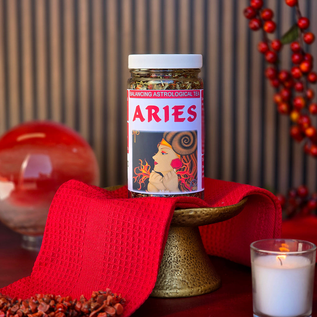 A jar of Aries Astrological Herbal Tea displayed on a gold pedestal with red accents, candlelight, and decorative elements for a bold zodiac-themed presentation.