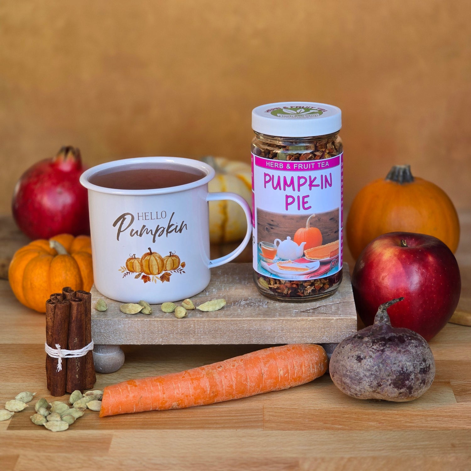 Pumpkin Pie Tea served in a white mug, surrounded by pumpkins, cinnamon sticks, apples, carrots, beets, cardamom, and other fall flavors from Herb Stop’s Fall Tea Collection