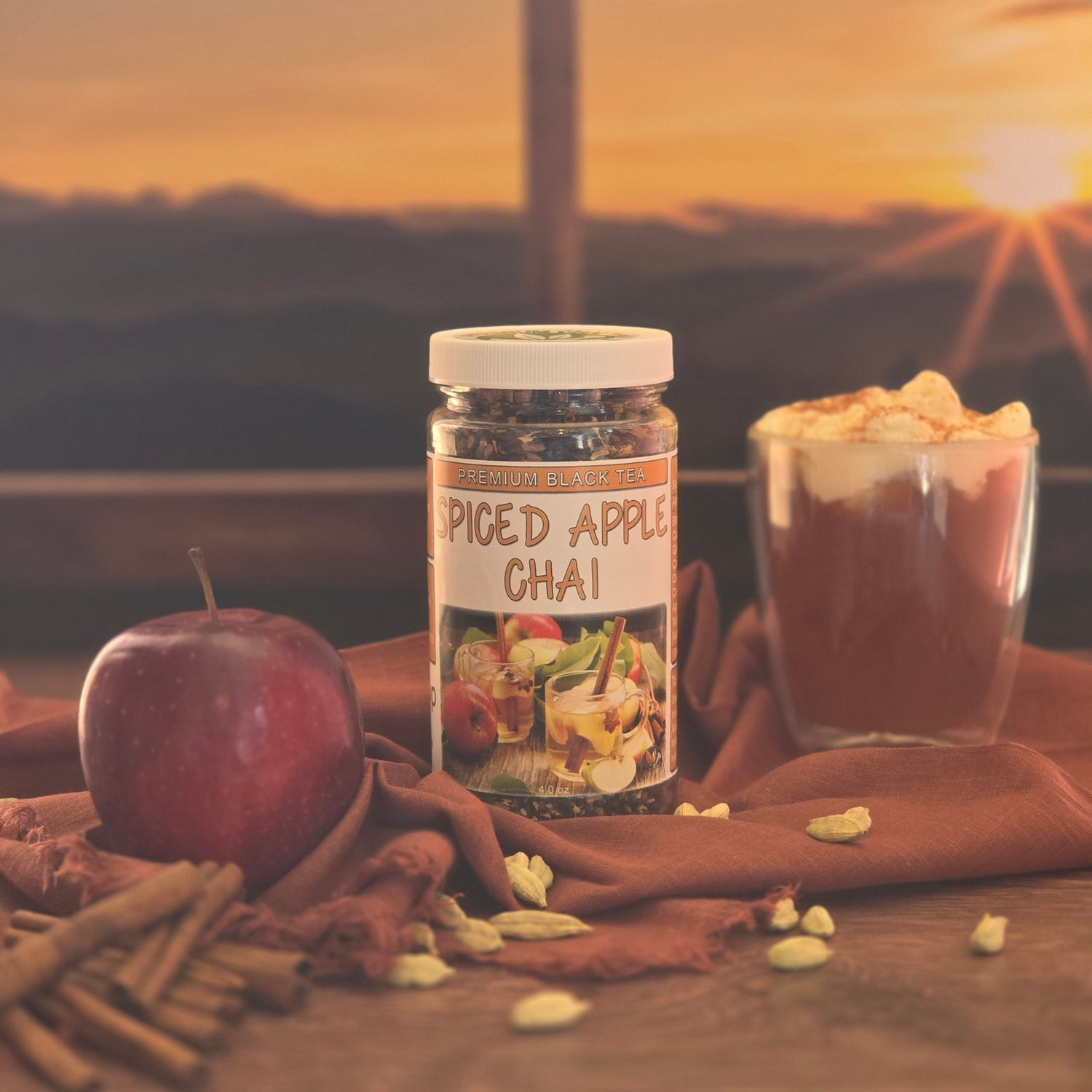Glass of spiced apple chai tea with cinnamon and cardamom beside a fresh apple at sunset