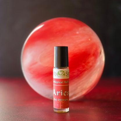 Aries Aromatherapy Roll-on bottle  in front of a red and white cinnabar quartz sphere on a dark background