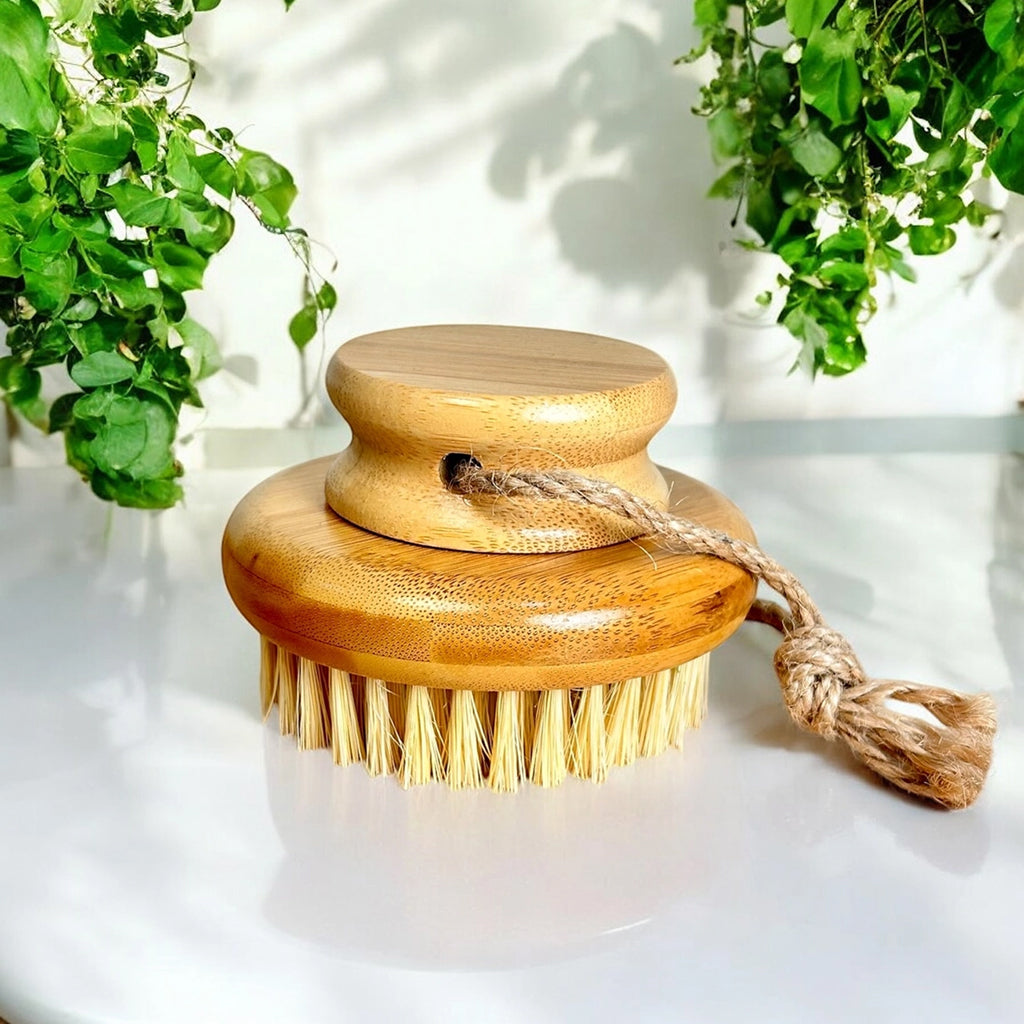 Bamboo dry body brush with sisal bristles on a white surface with greenery in the background