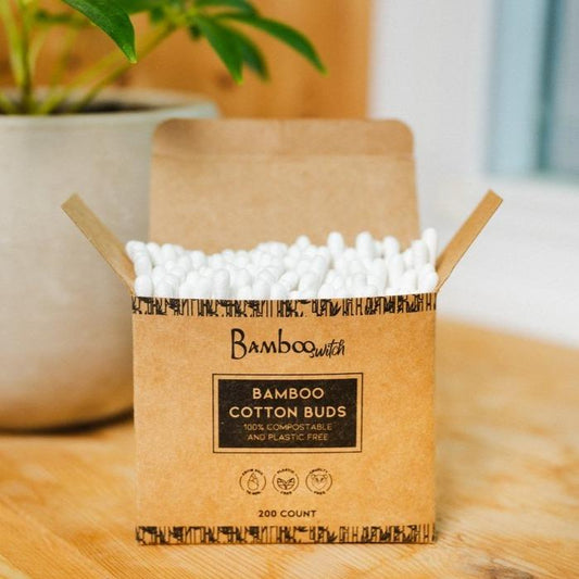 Box of Bamboo Switch bamboo cotton buds on a wooden surface with a plant in the background