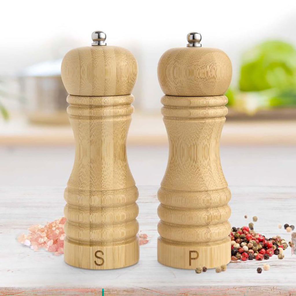 Bamboo salt and pepper shakers on a kitchen counter with spices around.
