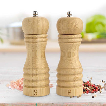Bamboo salt and pepper shakers on a kitchen counter with spices around.