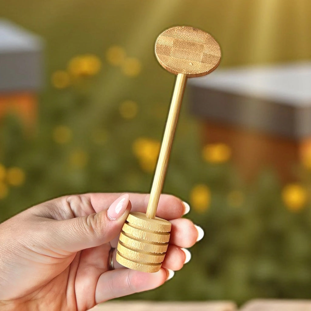 Hand holding a bamboo honey dipper with a blurred natural background
