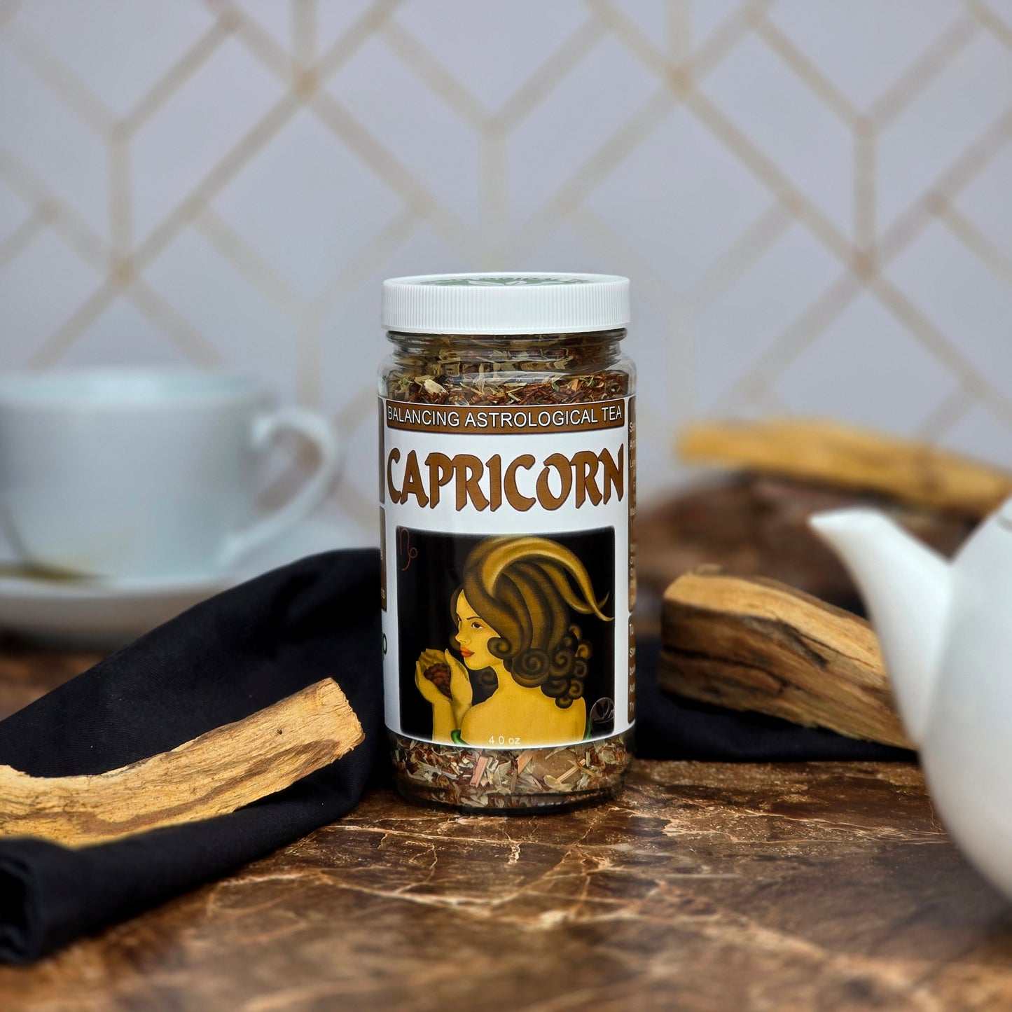 Jar of Capricorn astrological tea on a marble surface with a teapot and cup in the background.