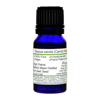 Blue bottle of Carrot Seed Oil with a label on a white background