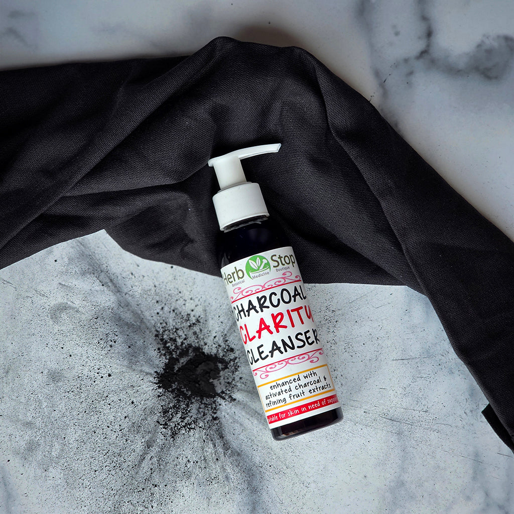 Charcoal Clarity Cleanser bottle on a marble surface with charcoal splatter
