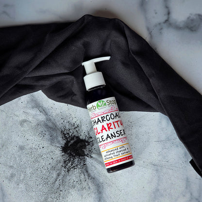 Charcoal Clarity Cleanser bottle on a marble surface with charcoal splatter
