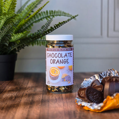 Jar of Chocolate Orange Black Tea on a wooden surface with a plant in the background