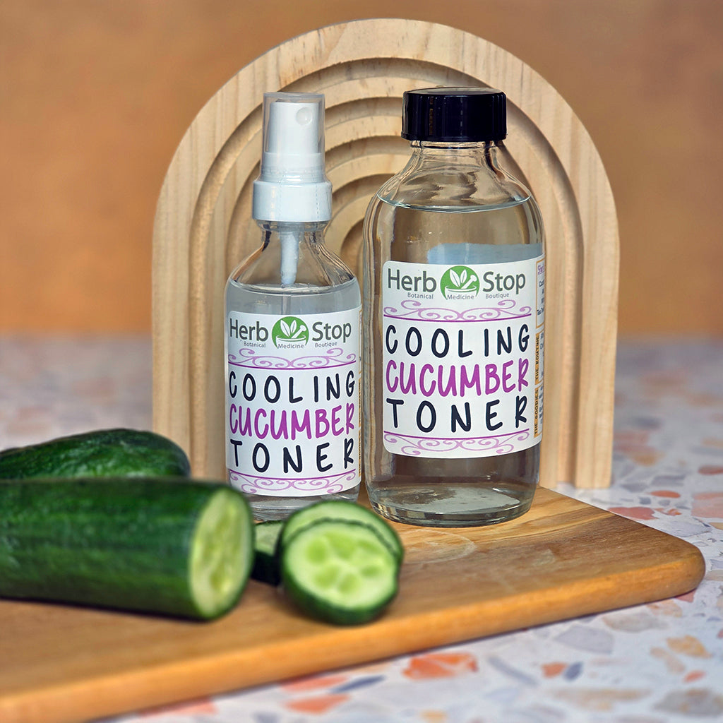 Two bottles of Herb Stop Cooling Cucumber Toner on a wooden board with cucumbers.