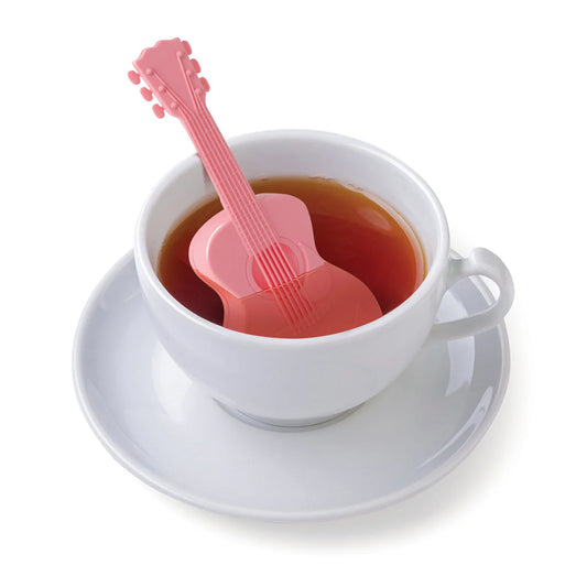 Pink guitar-shaped tea infuser in a cup of tea on a white background