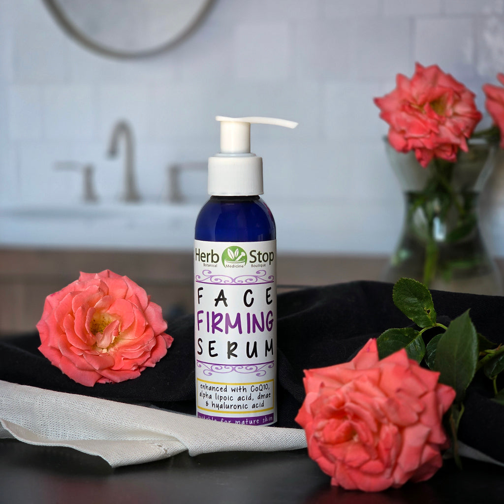 A bottle of Herb Stop Face Firming Serum with pink roses in a bathroom