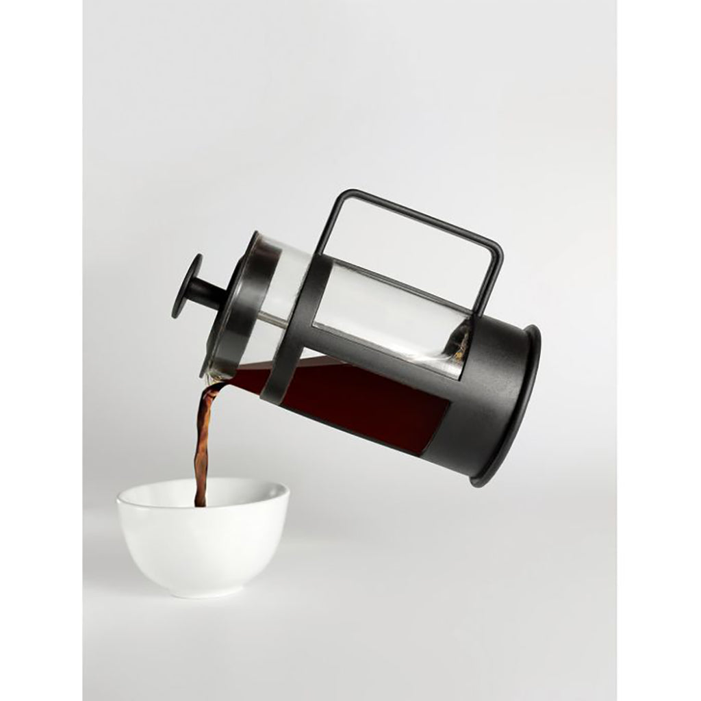 French press pouring coffee into a white cup on a light gray background