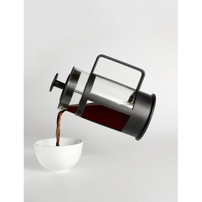 French press pouring coffee into a white cup on a light gray background