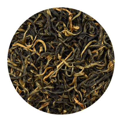 A circular close-up of golden monkey loose-leaf black tea leaves, showing dark brown to black rolled leaves mixed with lighter golden-brown and tan tips, isolated on a white background.