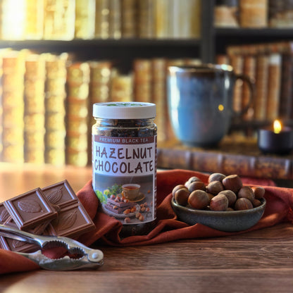Jar of Hazelnut Chocolate Black Tea in a library setting with chocolate and hazelnuts on a wooden surface