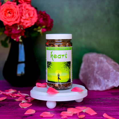 Heart Chakra Balancing Herbal Tea surrounded by rose petals with rose quartz in the background on a pink surface