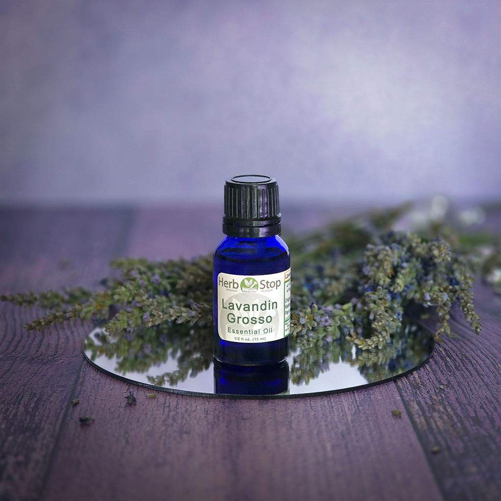 Bottle of Herb Stop Lavandin Grosso essential oil with lavender sprigs on a wooden surface