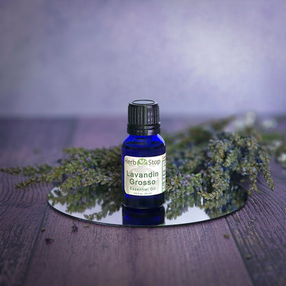Bottle of Herb Stop Lavandin Grosso essential oil with lavender sprigs on a wooden surface