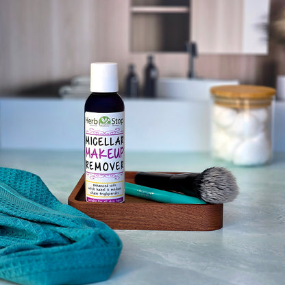 Herb Stop Micellar Makeup Remover bottle on a bathroom counter with a  makeup brush and towel.