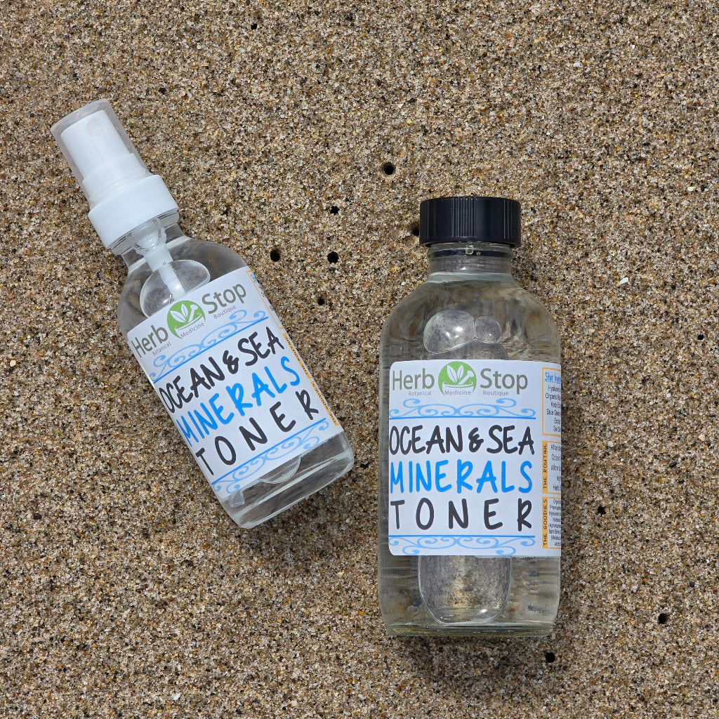 Bottles of Herb Stop Ocean & Sea Minerals Toner in the ocean sand